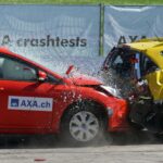 Red and yellow cars shown in a head-on collision during a crash test for safety evaluation.
